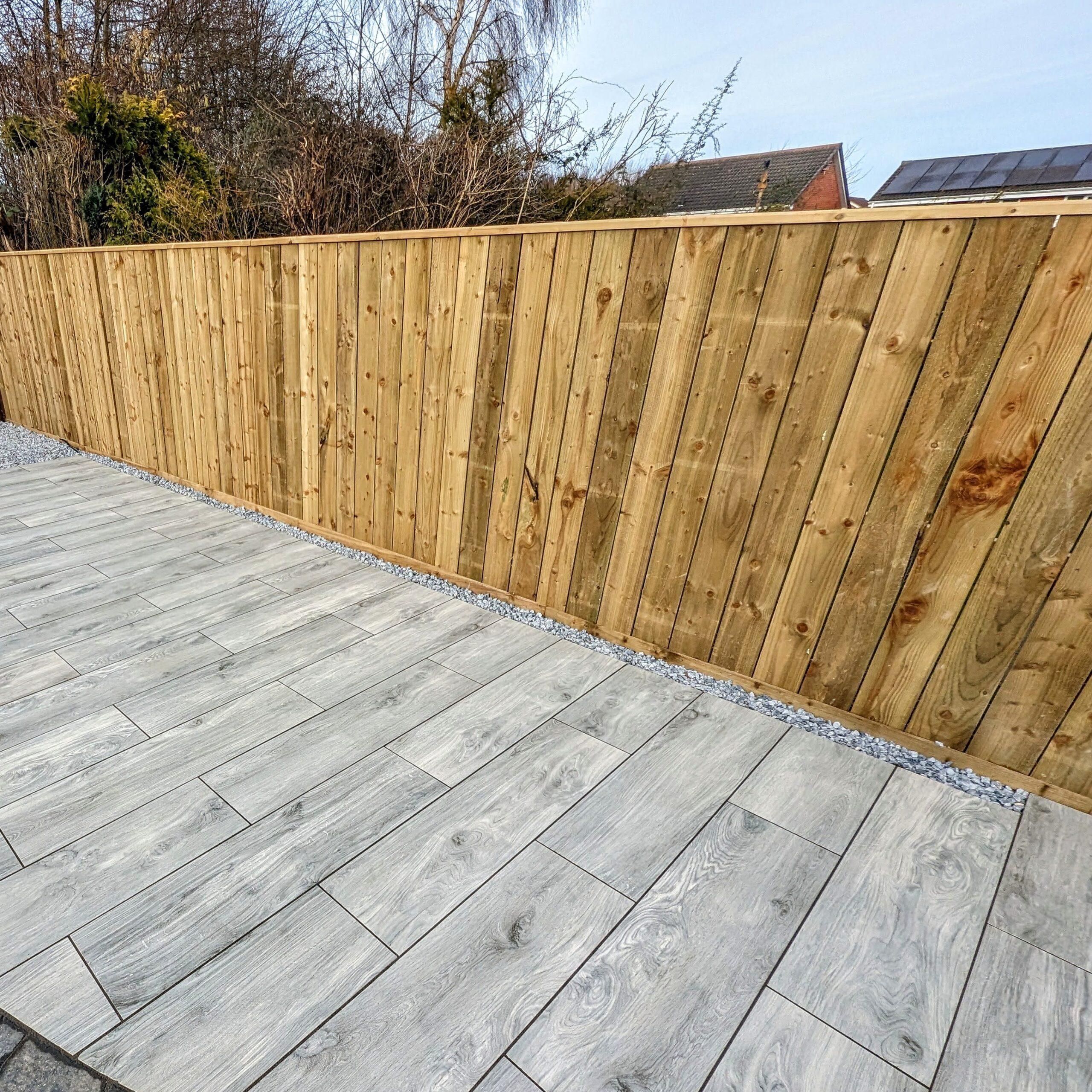 A line of fencing with a wooden patio beneath it.